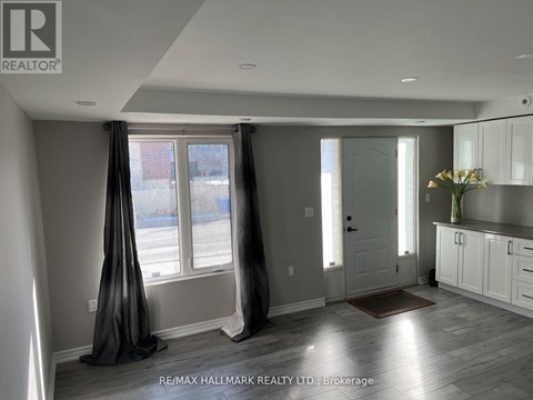 A well-lit, spacious room with a large window and a door leading to another room.