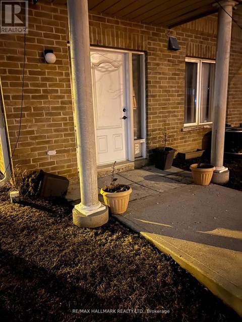 A white door is on the left side of a brick building.