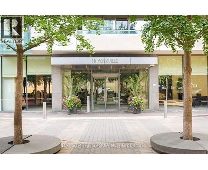 A realtor sign is on the left side of a building with a glass entrance.