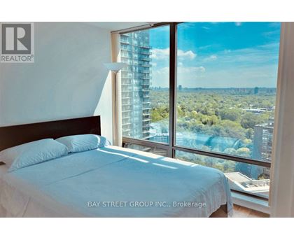 A bedroom with a large window overlooking a cityscape.