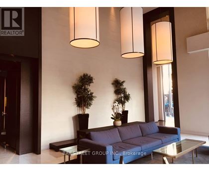 A living room with a couch, two potted plants, and two hanging lights.