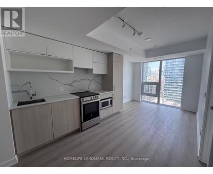 A modern kitchen with wooden floors and stainless steel appliances.