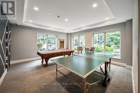 A spacious room with a ping pong table and a view of the backyard.