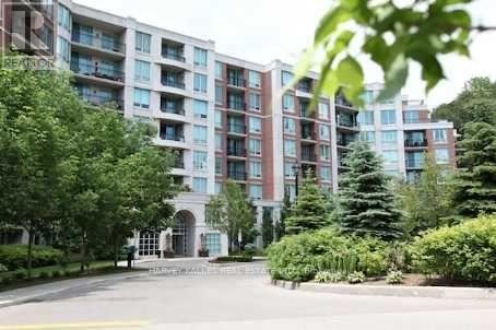 A large, modern apartment building with a landscaped courtyard in front.