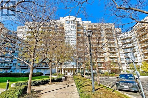 A car is parked on a street in front of a large apartment building.