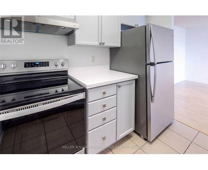 A kitchen with a stove top oven, white counter top, and a refrigerator.