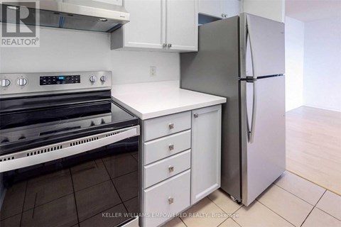 A kitchen with a stove top oven, white counter top, and a refrigerator.