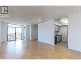 A spacious room with wooden flooring and white walls.