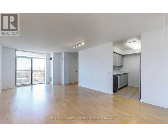 A spacious room with wooden flooring and white walls.