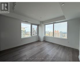A spacious room with a view of the cityscape through large windows.