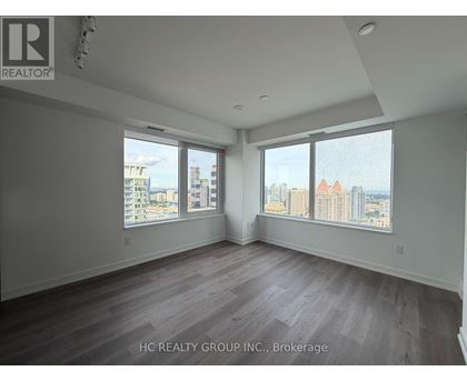 A spacious room with a view of the cityscape through large windows.