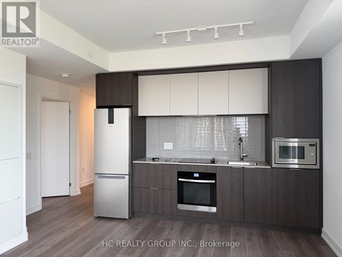 A modern kitchen with dark wood cabinets and stainless steel appliances.