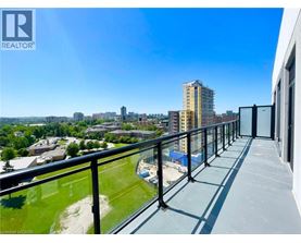 A balcony overlooks a cityscape with buildings and a clear blue sky.