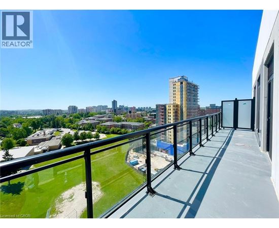 A balcony overlooks a cityscape with buildings and a clear blue sky.