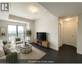 A living room with a television, a couch, a chair, a coffee table, and a plant.