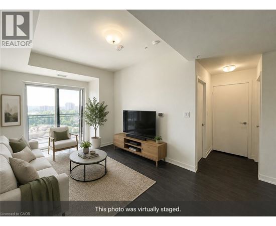 A living room with a television, a couch, a chair, a coffee table, and a plant.