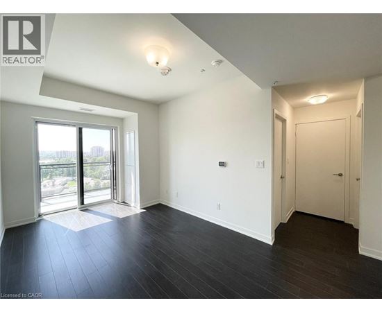 A spacious room with a sliding glass door leading to a balcony.