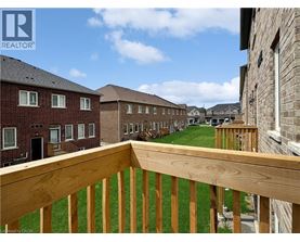 A wooden balcony overlooks a grassy area with apartment buildings in the background.