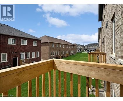 A wooden balcony overlooks a grassy area with apartment buildings in the background.