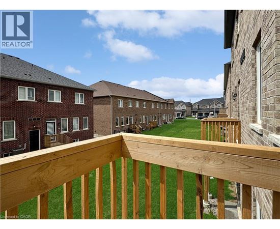 A wooden balcony overlooks a grassy area with apartment buildings in the background.