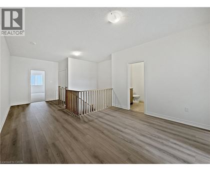 A spacious room with wood flooring and white walls.