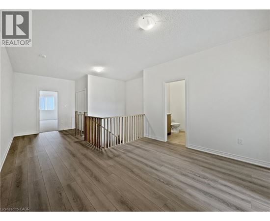 A spacious room with wood flooring and white walls.