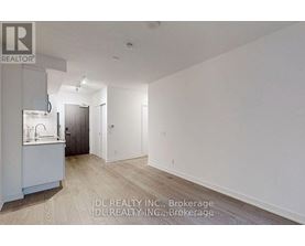 A spacious, empty room with wood flooring and white walls.