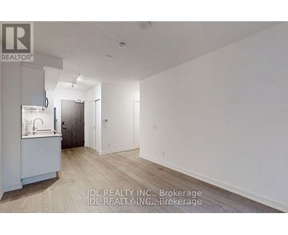 A spacious, empty room with wood flooring and white walls.