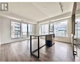 A spacious room with wooden flooring and large windows overlooking a cityscape.