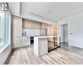 A modern kitchen with a central island and wooden flooring.
