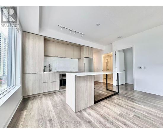 A modern kitchen with a central island and wooden flooring.