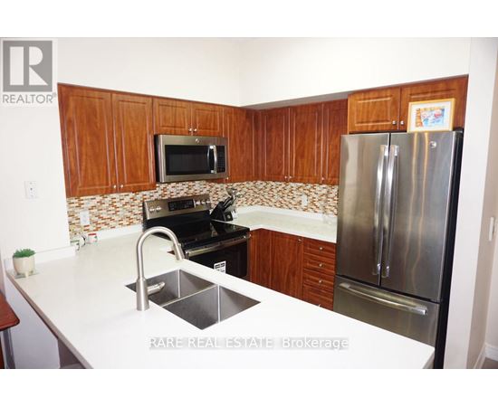 A kitchen with a refrigerator, sink, and microwave.
