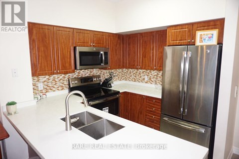 A kitchen with a refrigerator, sink, and microwave.