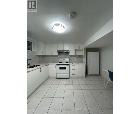 A white kitchen with a stove top oven and a refrigerator.
