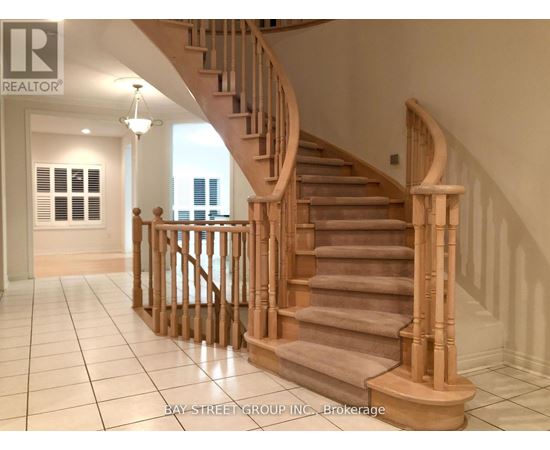 A wooden staircase with a carpeted runner leads up to a bright room with a window.
