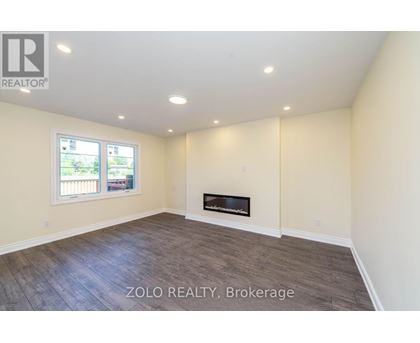A room with a fireplace and a window with a view of a fence and trees.