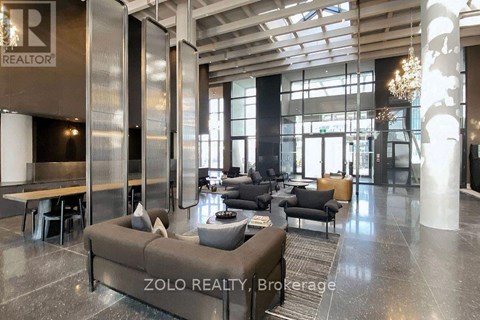 A modern living room with a large sofa and a chandelier.