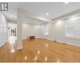 A spacious room with wooden flooring and white walls.