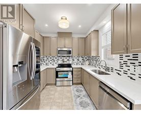 A modern kitchen with a stainless steel refrigerator and a black and white tiled backsplash.