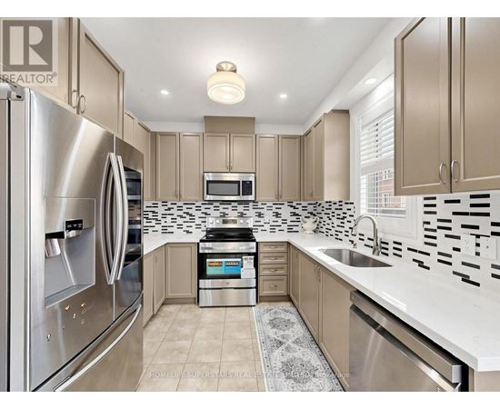 A modern kitchen with a stainless steel refrigerator and a black and white tiled backsplash.