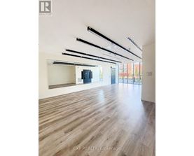 A spacious room with wooden flooring and a series of black beams on the ceiling.
