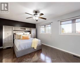 A bedroom with a bed, dresser, and ceiling fan.