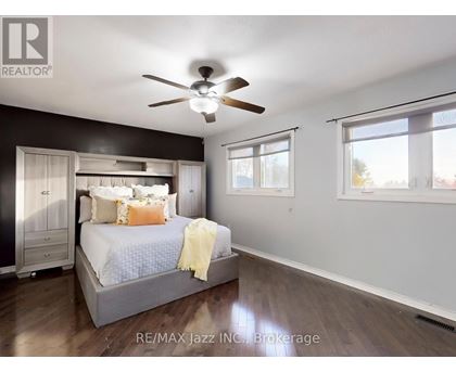 A bedroom with a bed, dresser, and ceiling fan.