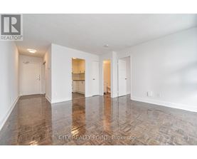 A spacious room with wood flooring and white walls.