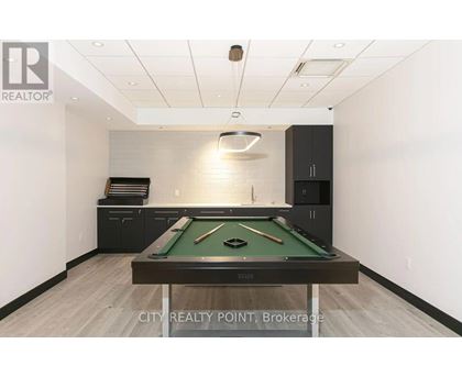 A pool table in a room with a realtor sign.