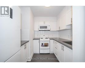 A white kitchen with a stove top oven and microwave.