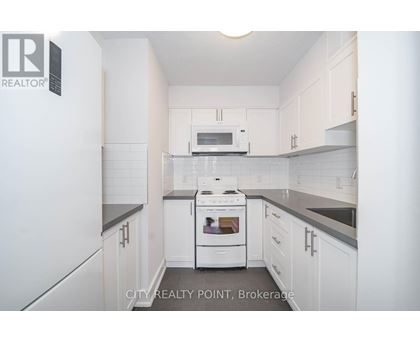 A white kitchen with a stove top oven and microwave.