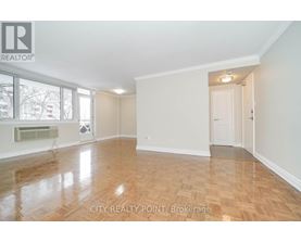 A spacious room with wooden flooring and white walls, with a doorway leading to another room.