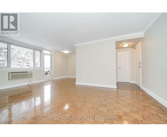 A spacious room with wooden flooring and white walls, with a doorway leading to another room.