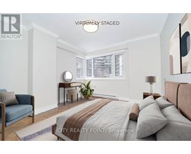 A bedroom with a bed, a chair, and a painting on the wall.